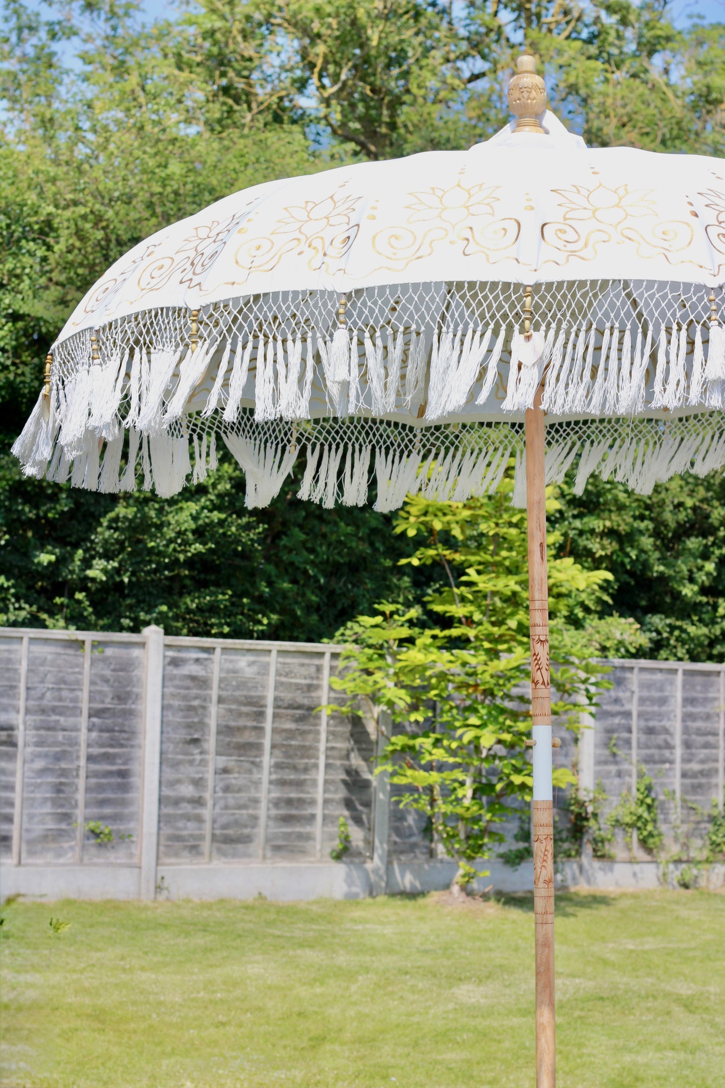 Gold and white garden parasol with carved wooden pole and decorative handmade details