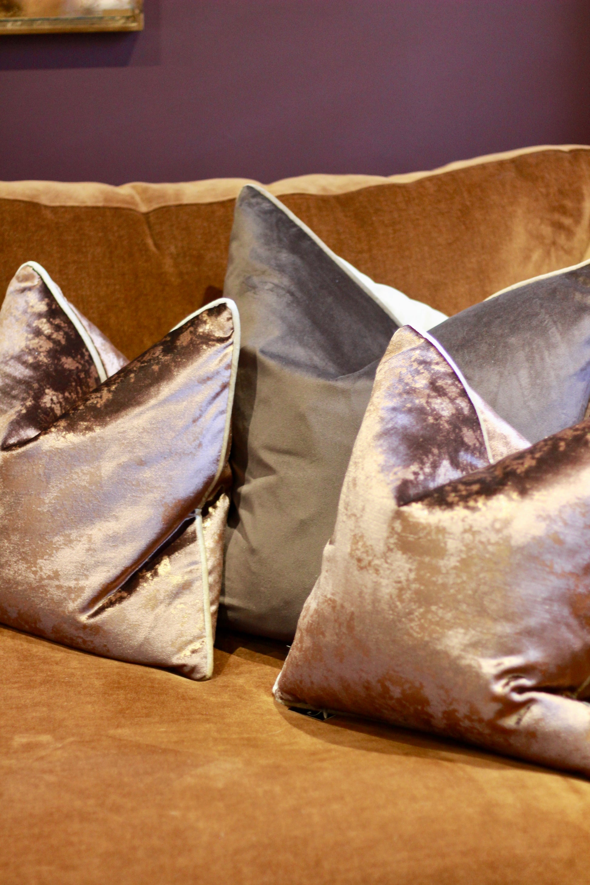 Side view of plump chocolate metallic cushion with feather-filled inner.