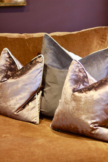 Side view of plump chocolate metallic cushion with feather-filled inner.