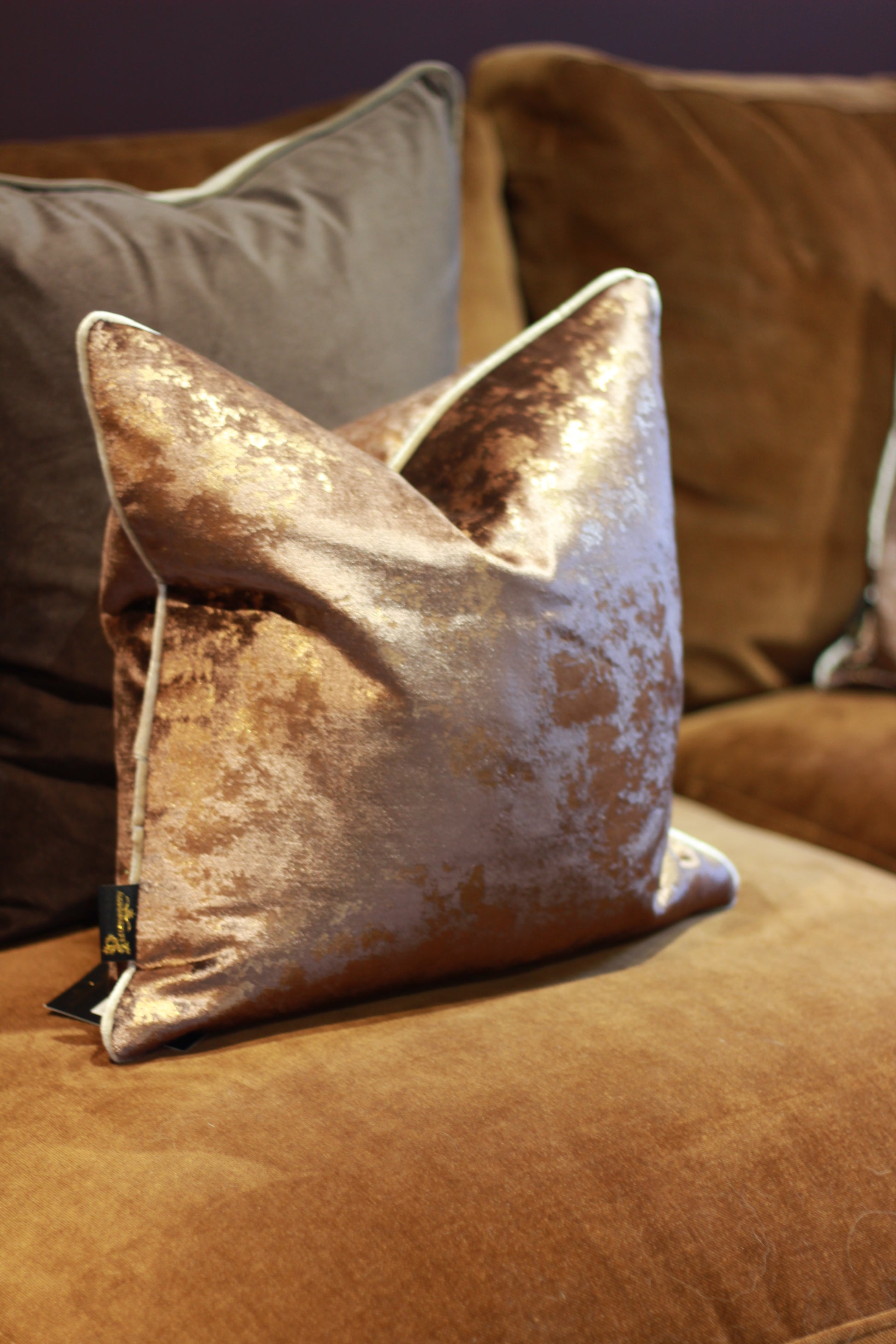 Luxury chocolate metallic fleck cushion displayed on a neutral brown sofa.