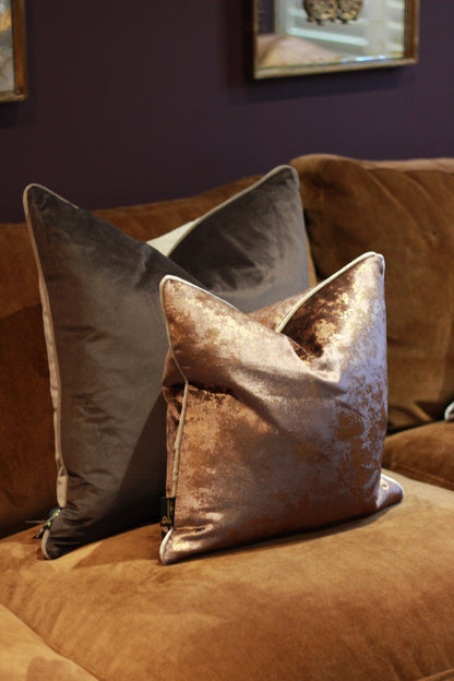 Chocolate metallic velvet cushion styled on a warm brown sofa.
