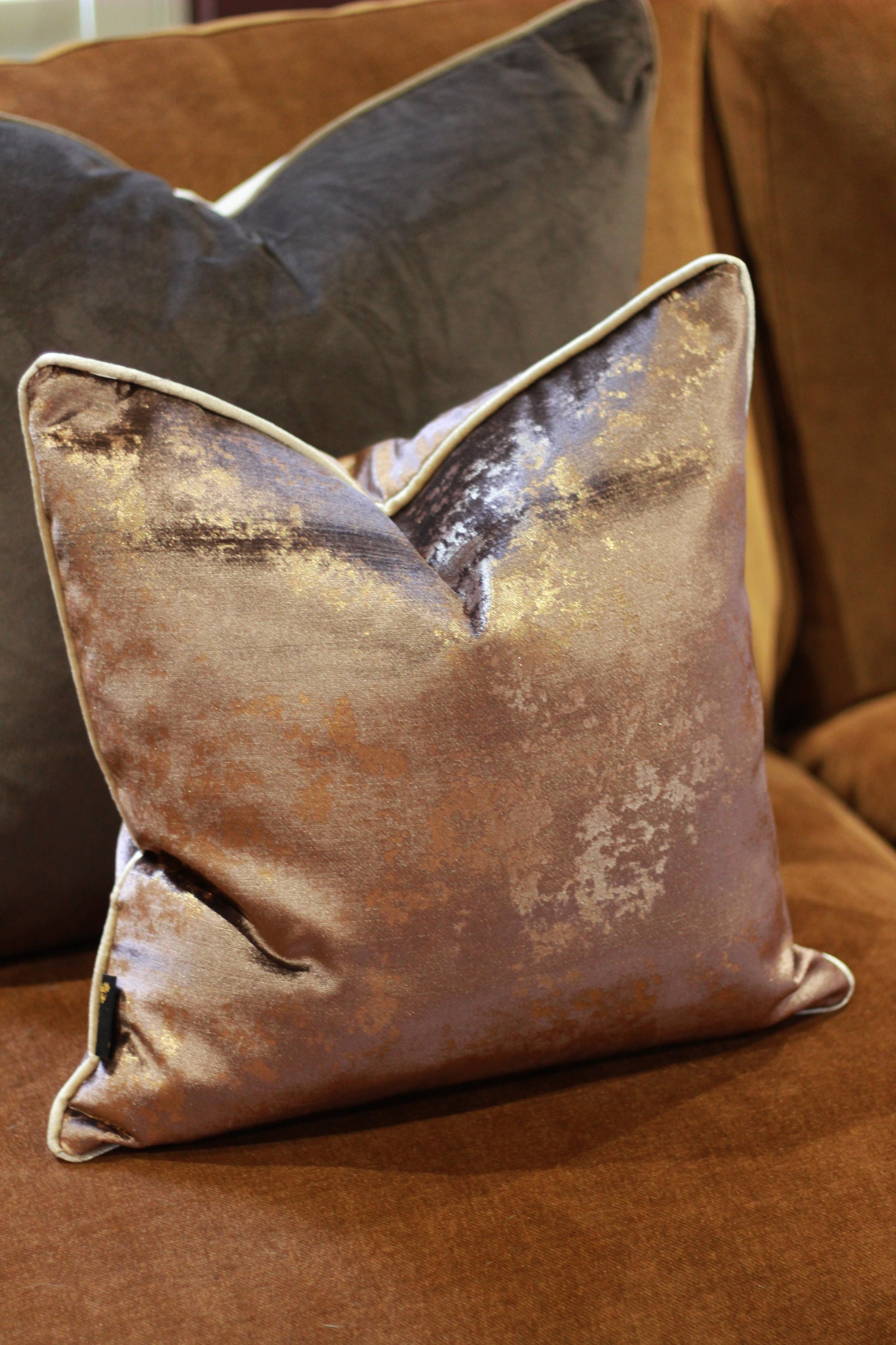 Close-up of the shimmering metallic finish on the chocolate velvet cushion.