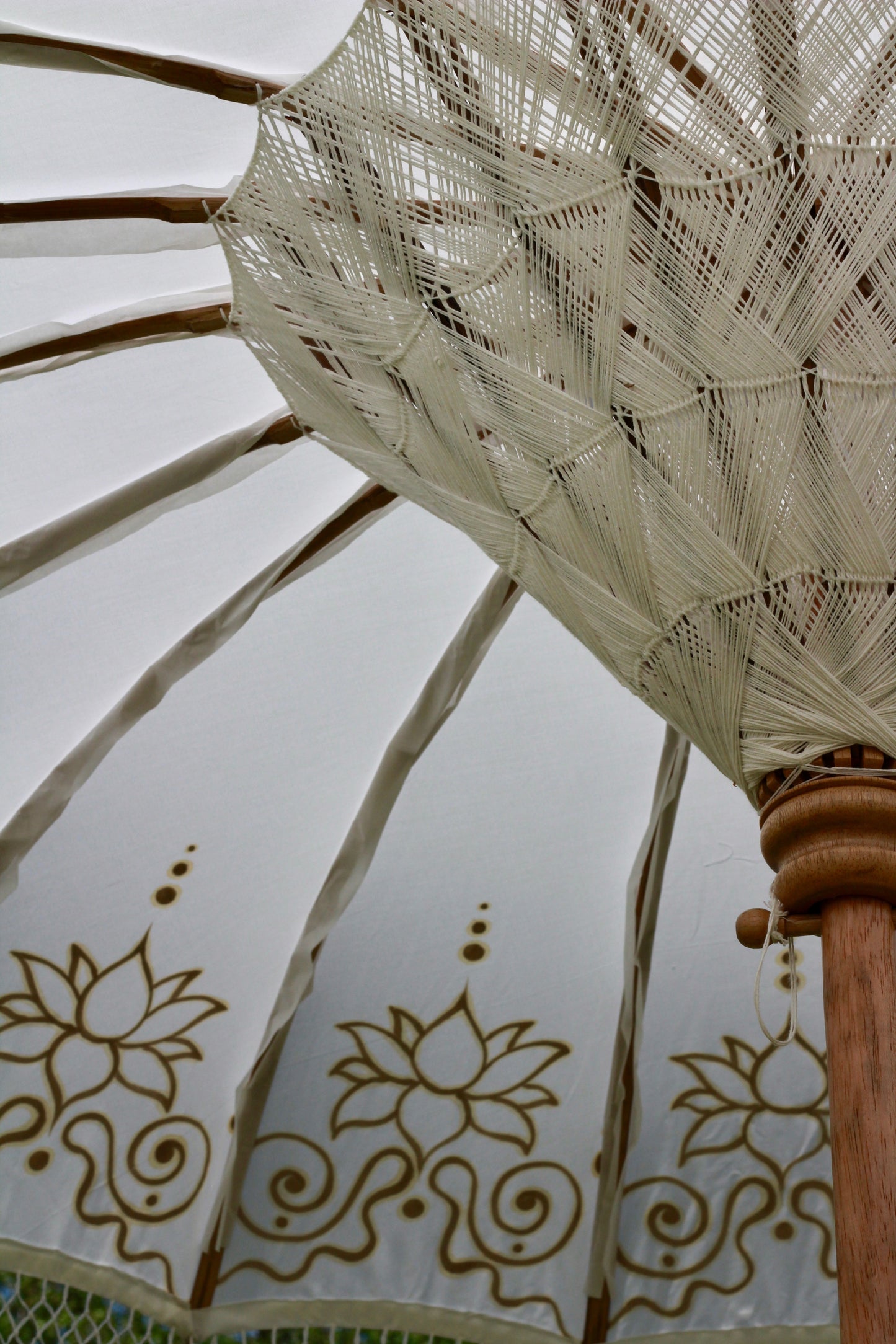 Decorative Balinese-style garden parasol with gold floral detailing on a white canopy