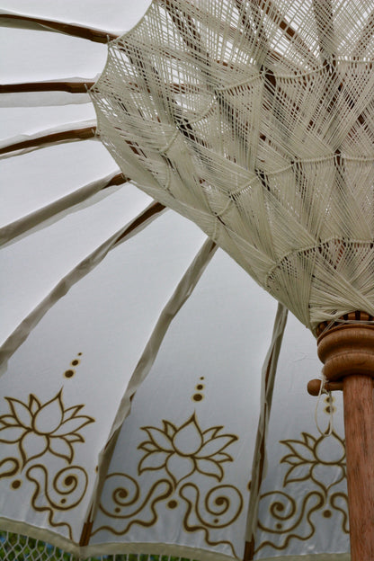 Decorative Balinese-style garden parasol with gold floral detailing on a white canopy