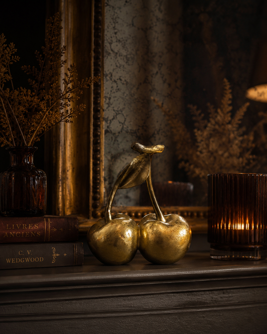 Decorative gold cherries styled in an elegant layered interior.