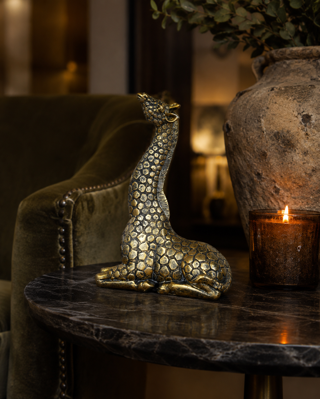 Gold resin giraffe ornament displayed with layered home accessories.