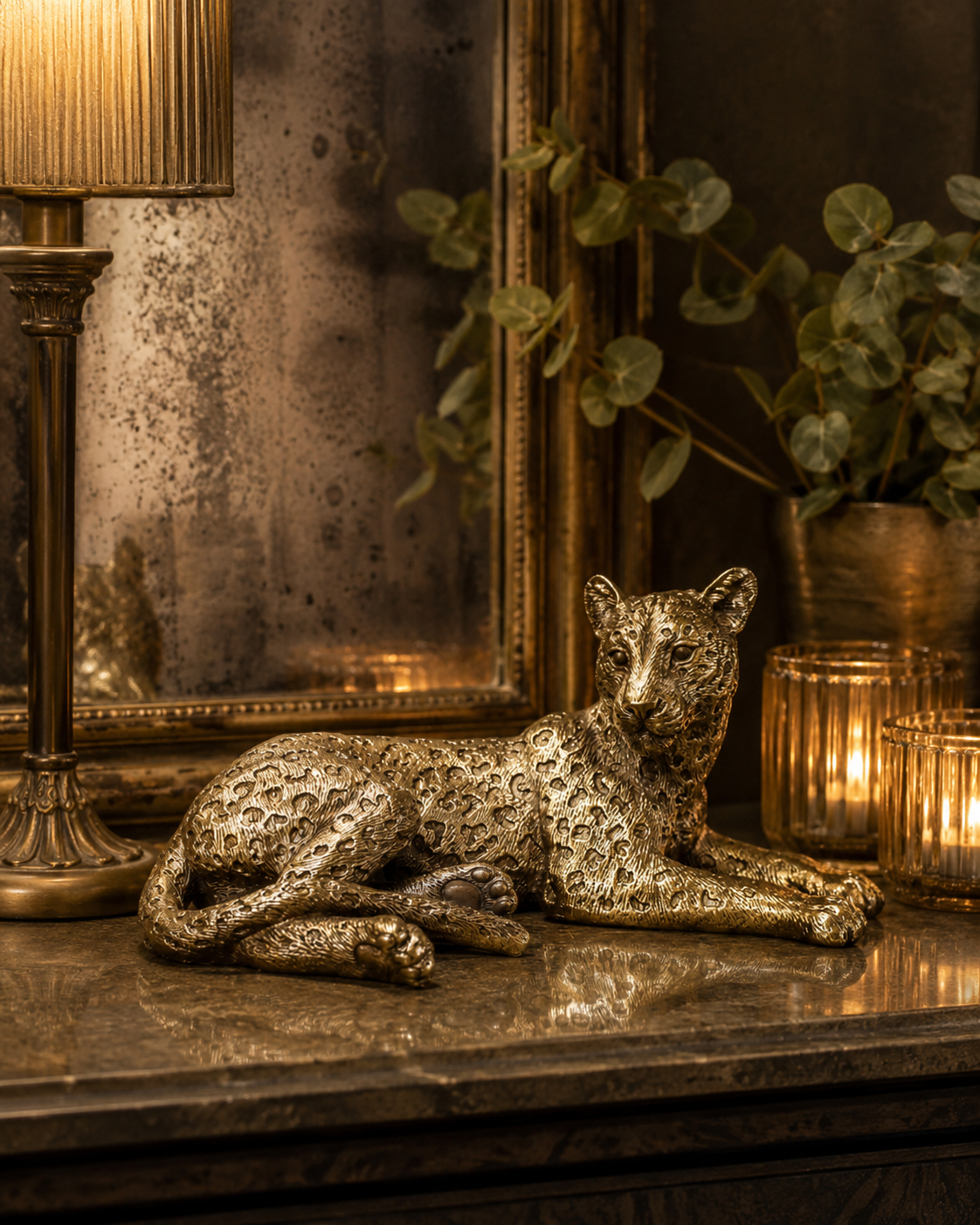 Decorative reclining gold leopard sculpture styled on a shelf.