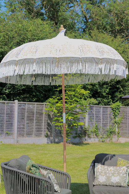Gold and white handmade Balinese-style garden parasol styled outdoors as a statement garden feature