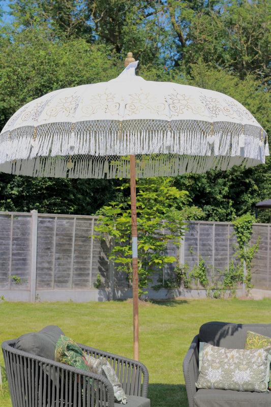 Gold and white handmade Balinese-style garden parasol styled outdoors as a statement garden feature