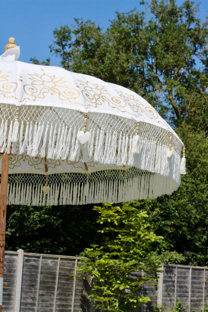 Gold and white Balinese-style parasol with decorative fringe and tassel edging
