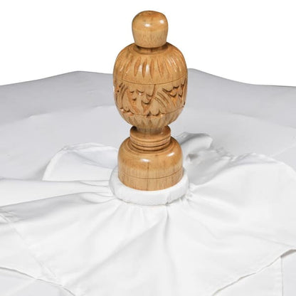 Close up of the carved wooden finial on a gold and white handmade Balinese-style garden parasol