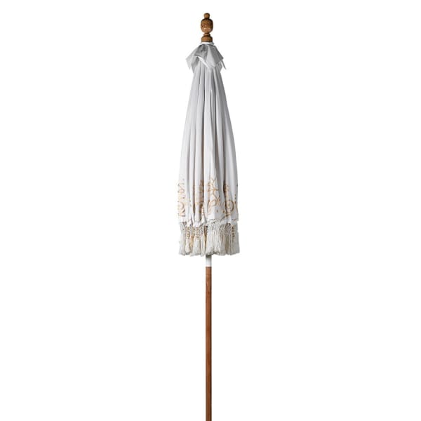 Gold and white Balinese-style garden parasol shown closed with decorative fringe and wooden pole