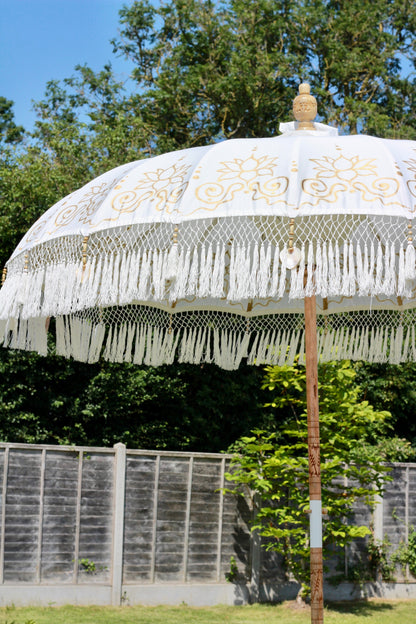 Gold and white garden parasol styled with outdoor seating for a relaxed summer garden look