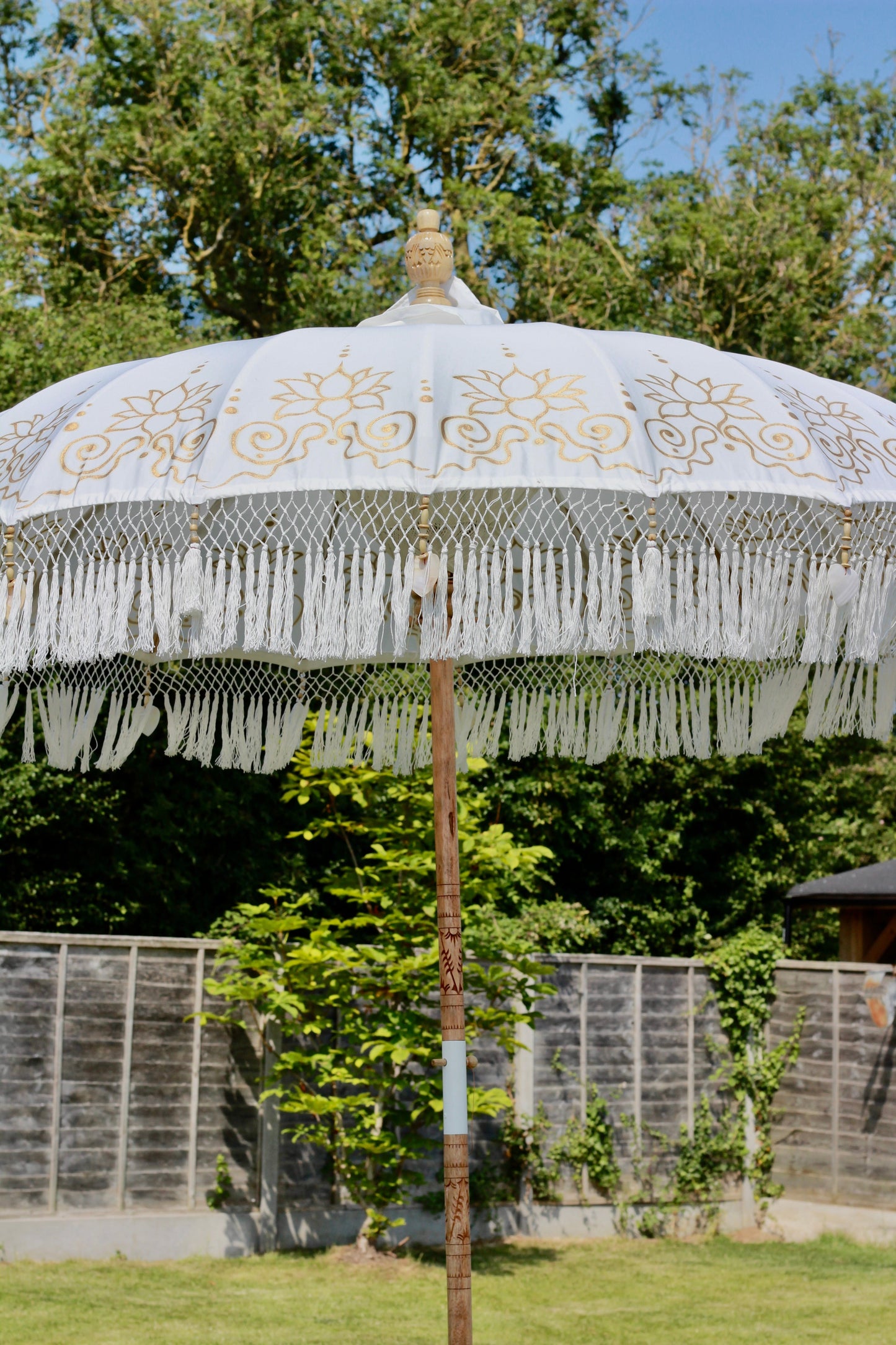 Handmade Balinese-style parasol in white and gold with decorative fringed edge